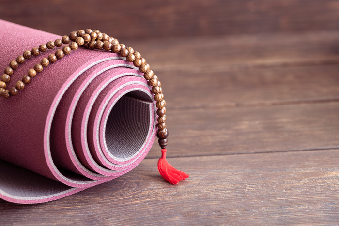 Rolled yoga mat  for hatha yoga practice and tibetan mala beads for meditation or mindfulness.
